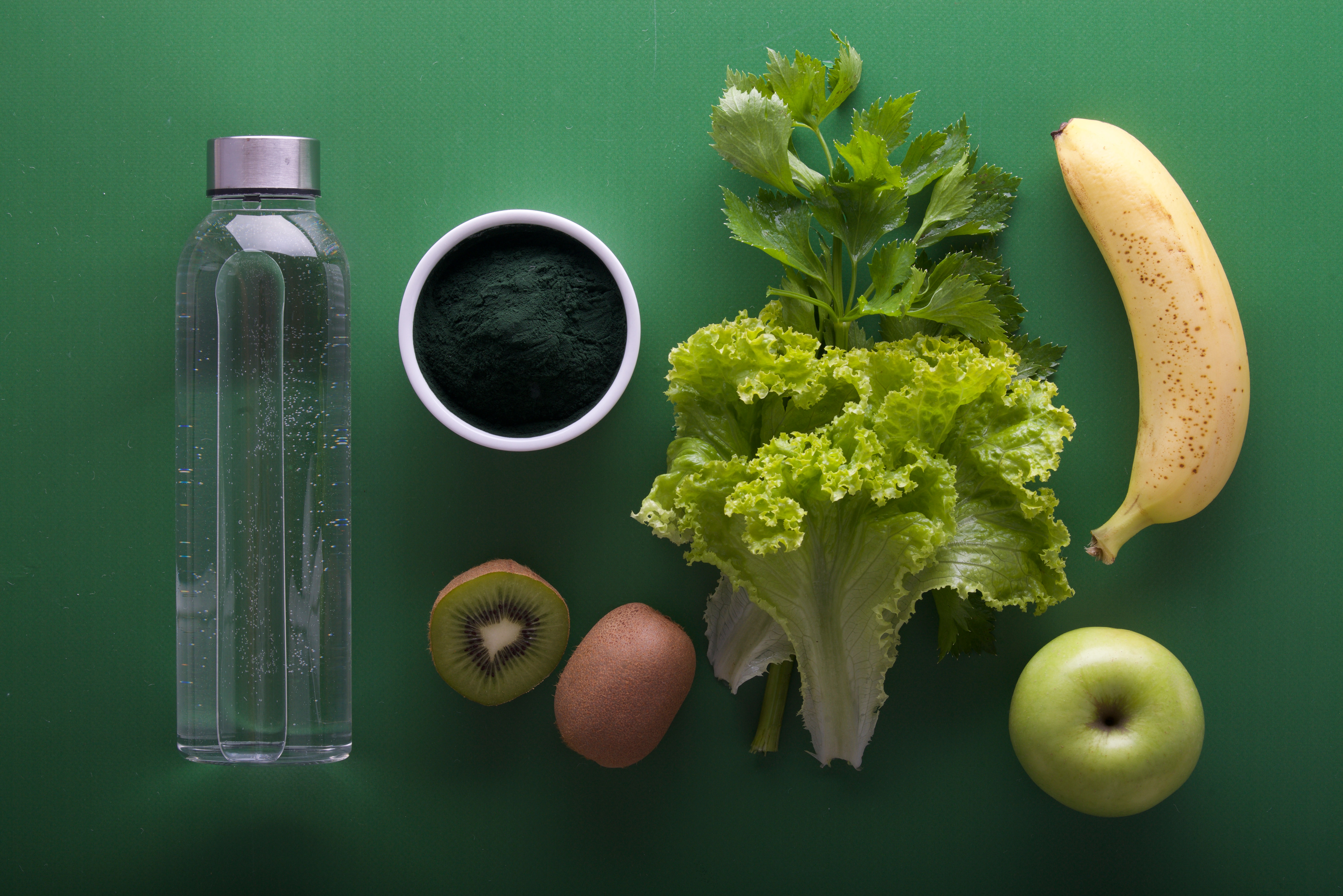 minerali nel corpo umano dove si trovano - verdura a foglia verde e frutta e bottiglia d'acqua