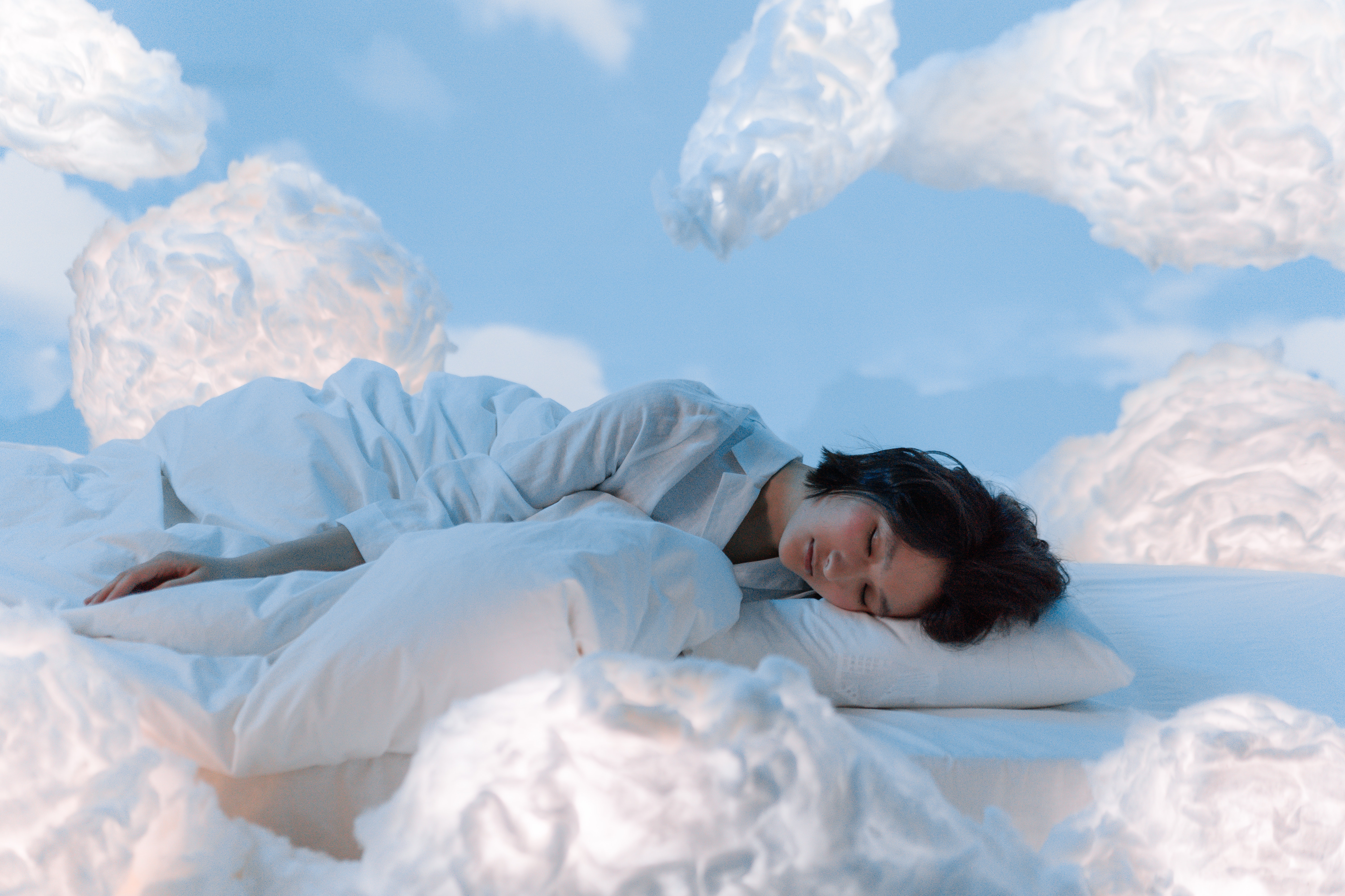 disturbi del sonno e magnesio - donna che dorme serena tra nuvole e cuscini
