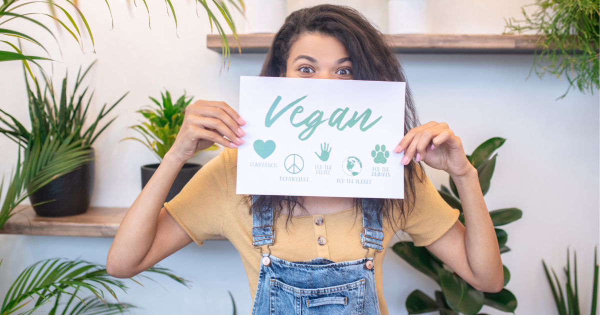 integratori e dieta vegana - ragazza che mostra cartello con la scritta vegan davanti al viso